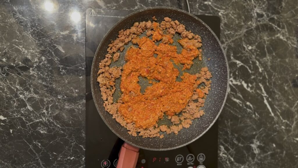 Mešanje sosa od pečene paprike sa kobasicom.