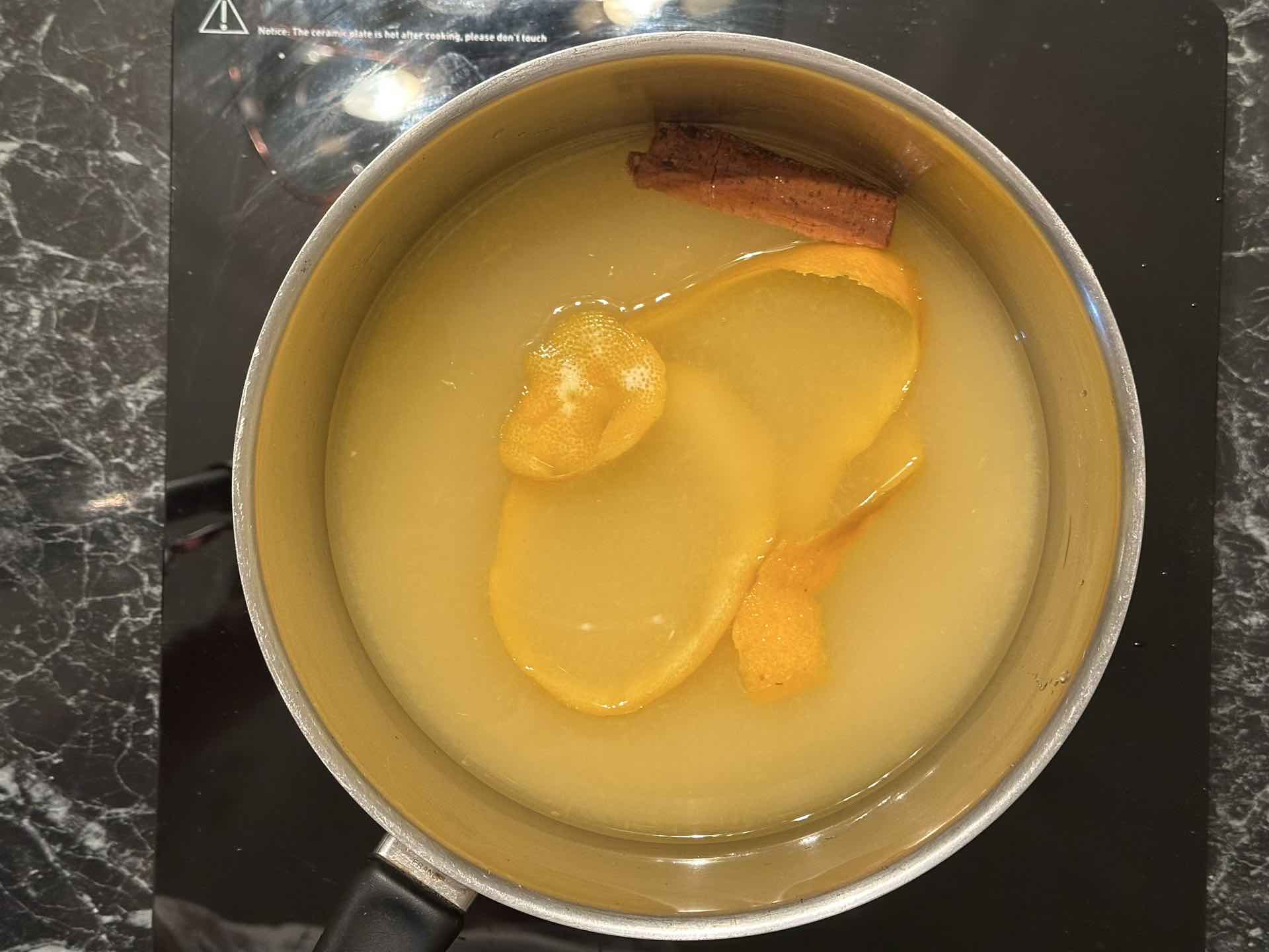 Sirup od narandže sa šećerom, korom narandže i cimetom u šerpi