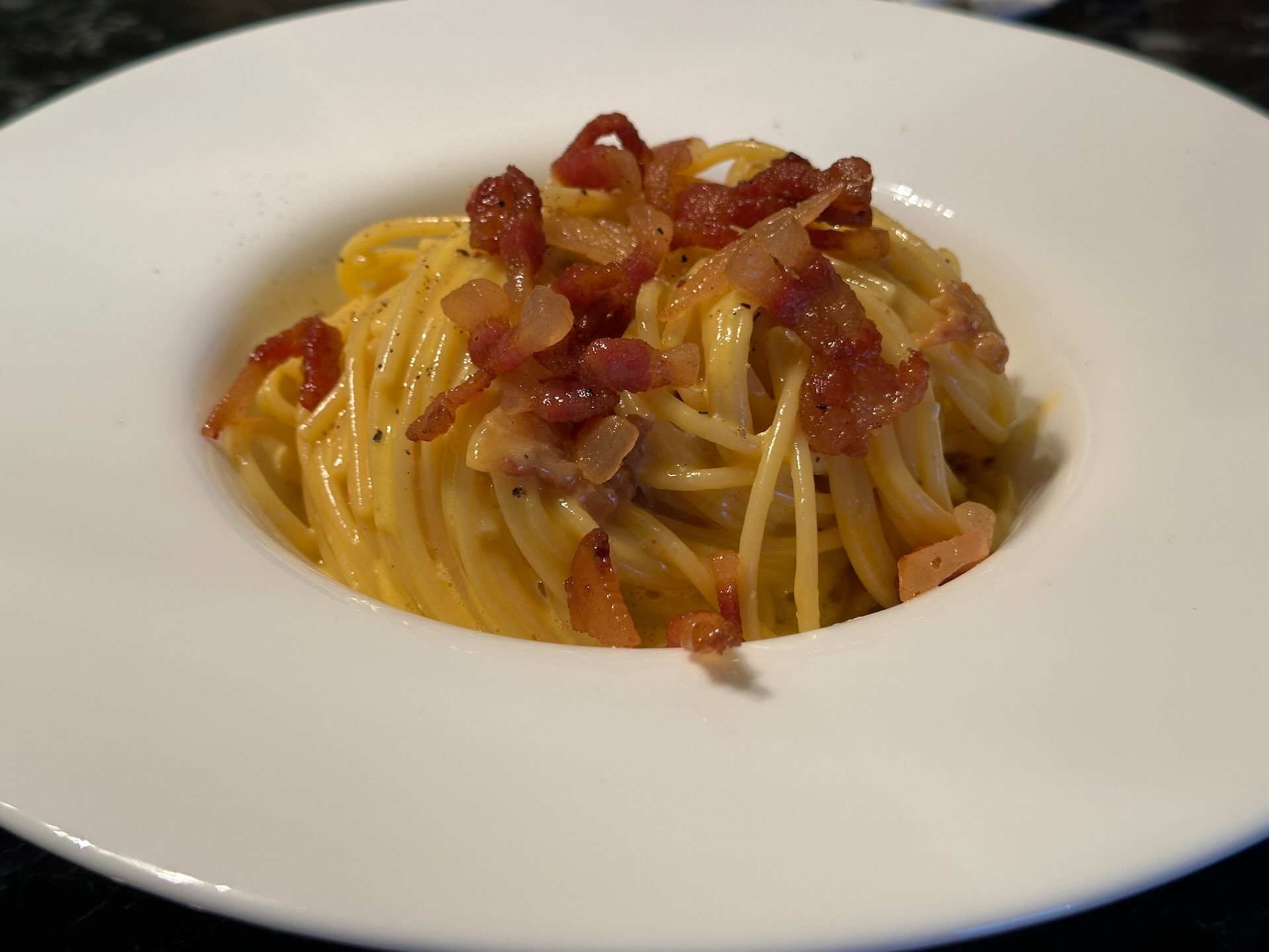 Serviranje špageta sa prženom guanciale slaninom, sosom i mlevenim biberom