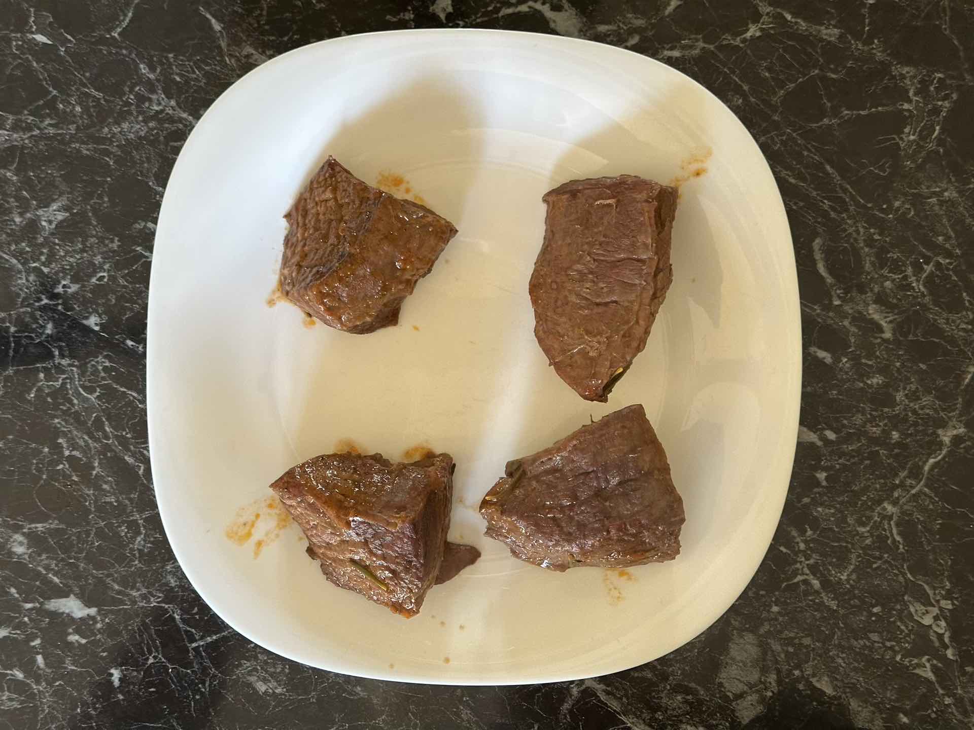 Četiri komada dinstane junetine odložena na tanjir nakon kuvanja