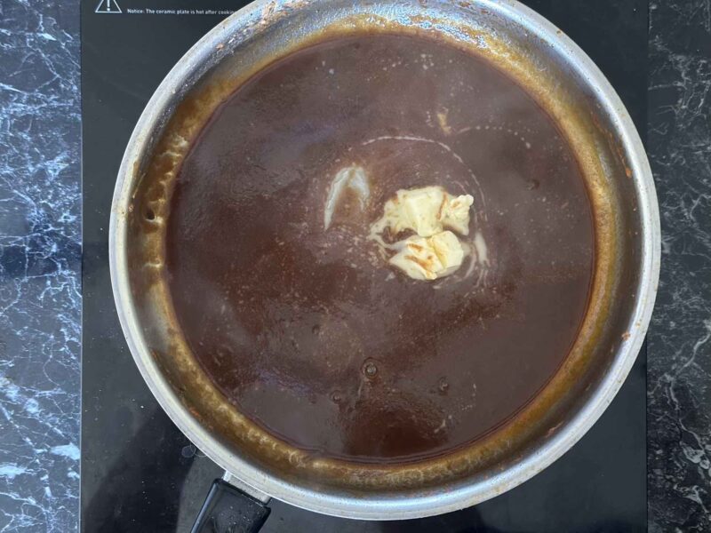 Komadići maslaca tope se u tamnom sosu od crvenog vina