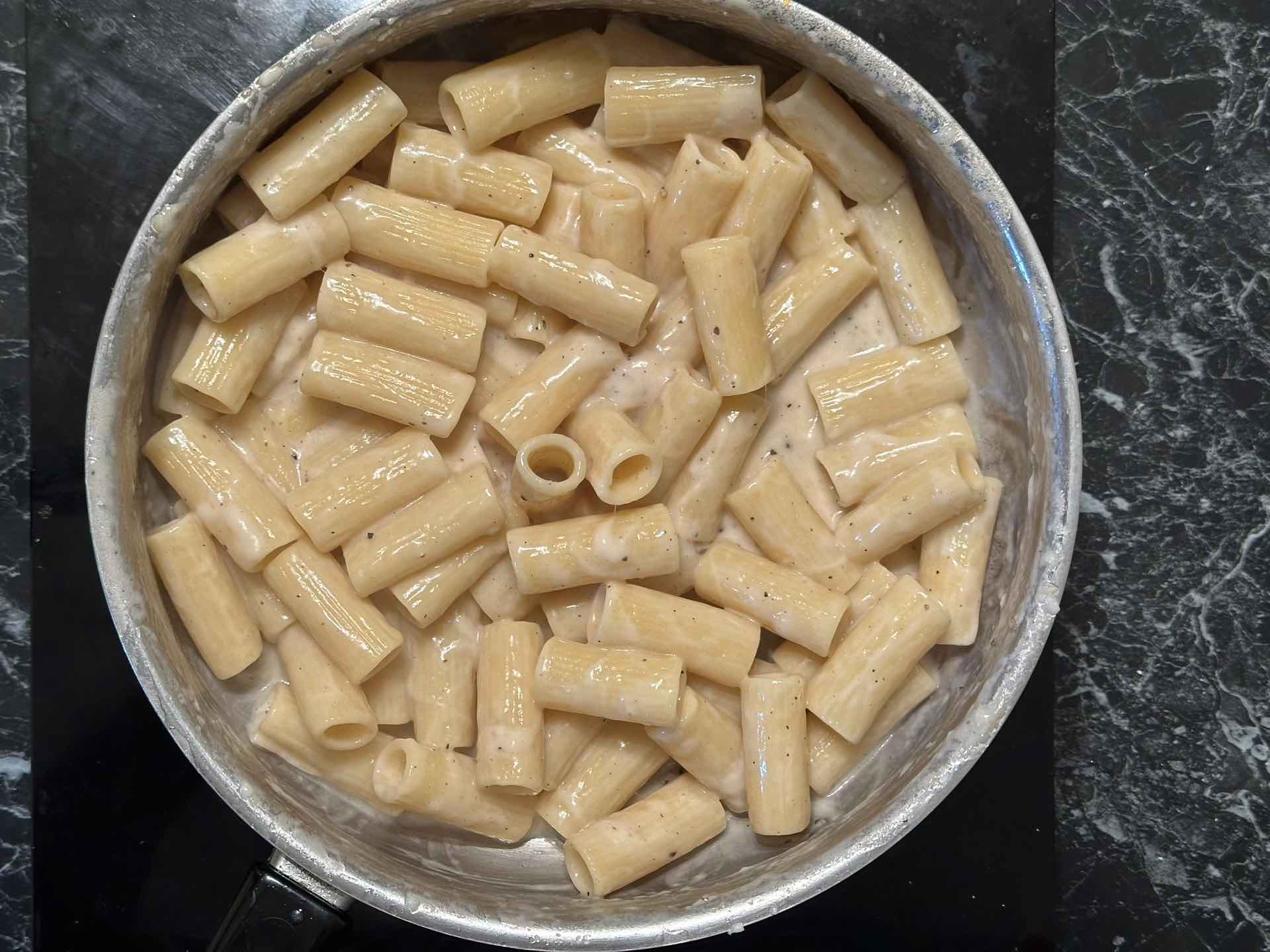 Rigatoni testenina i pekorino krema tokom spajanja u tiganju.